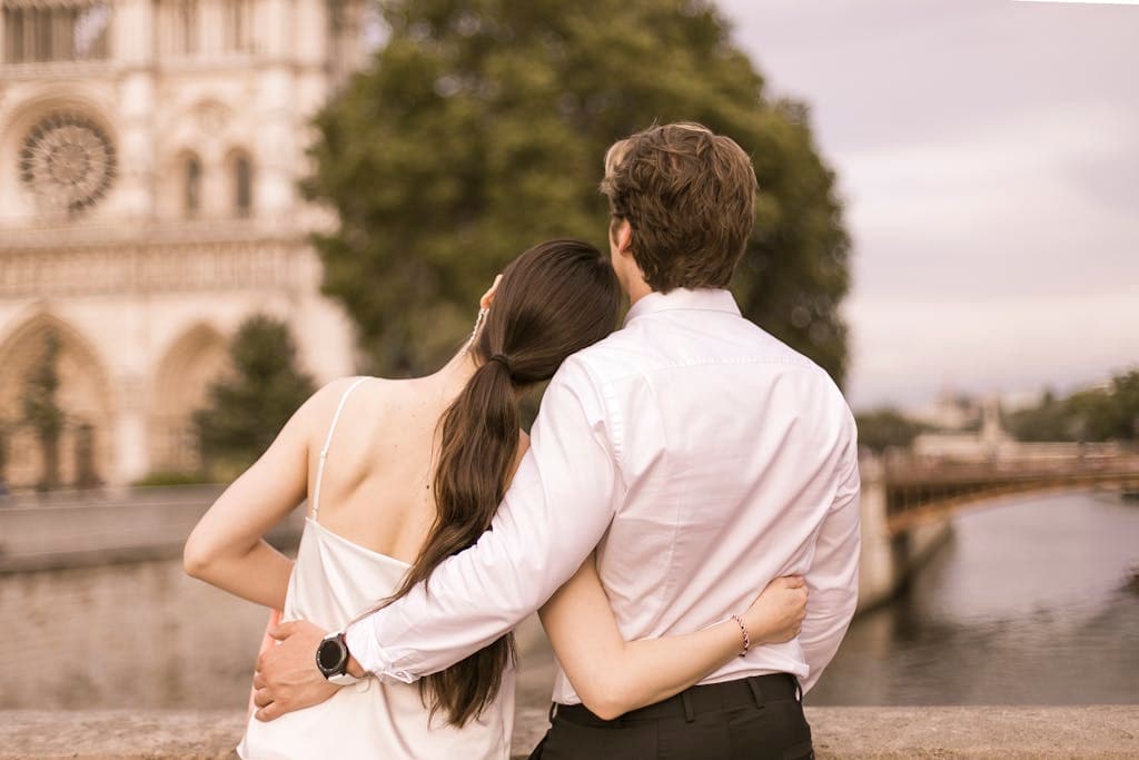 A couple embraces near Notre Dame, Paris, symbolizing love and travel romance.