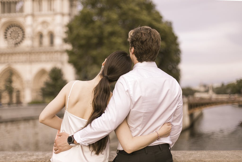 A couple embraces near Notre Dame, Paris, symbolizing love and travel romance.