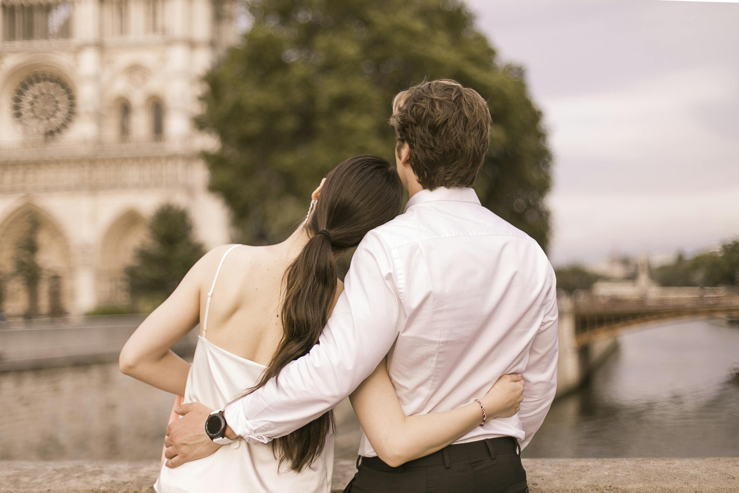 A couple embraces near Notre Dame, Paris, symbolizing love and travel romance.