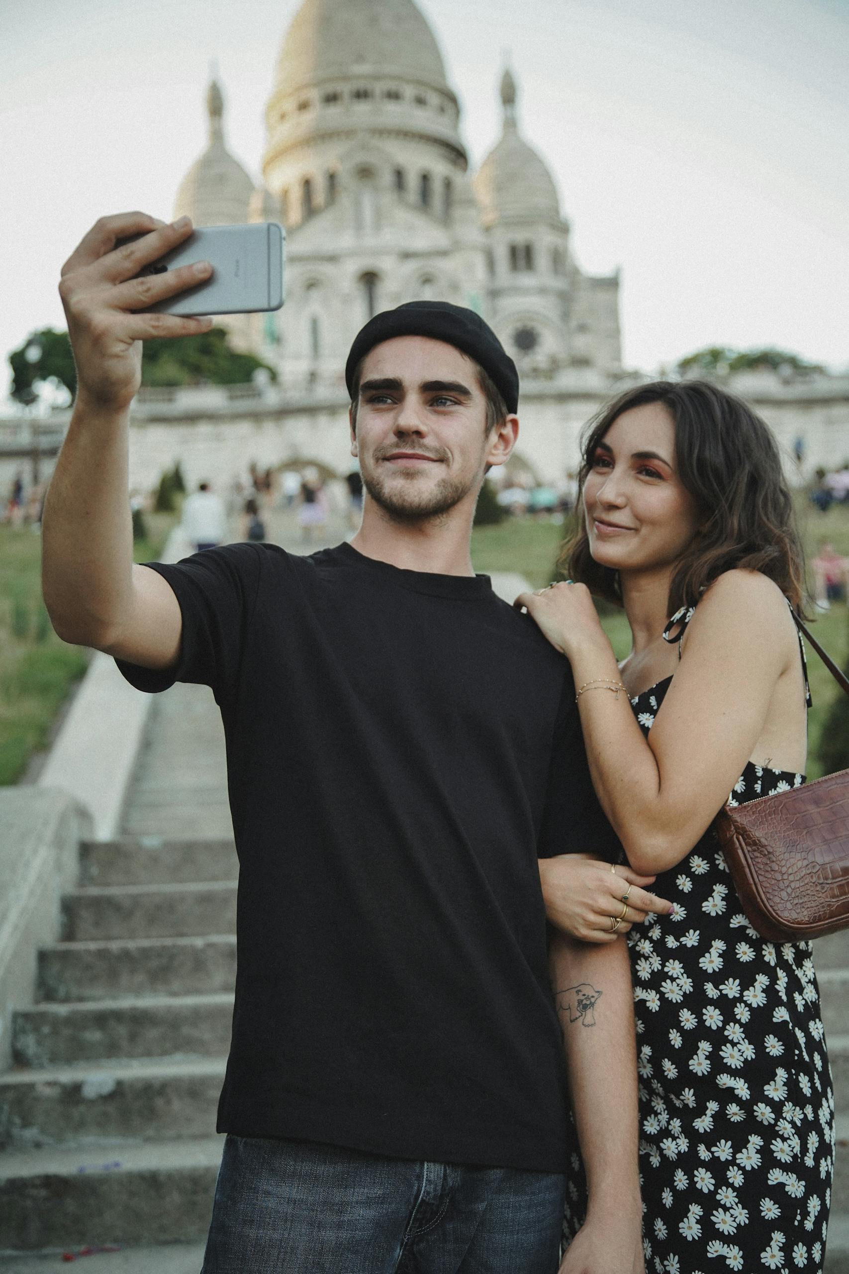 A happy couple capturing a moment at Sacré-Cœur on a sunny day.