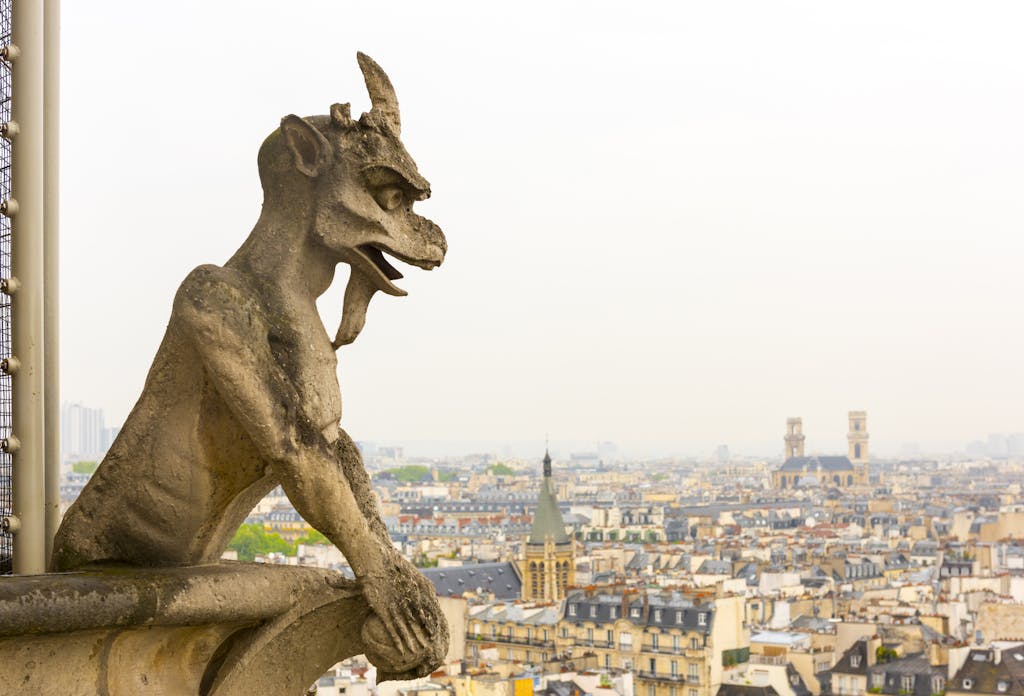 A stone gargoyle overlooks the stunning Paris cityscape, featuring historic architecture and iconic landmarks.