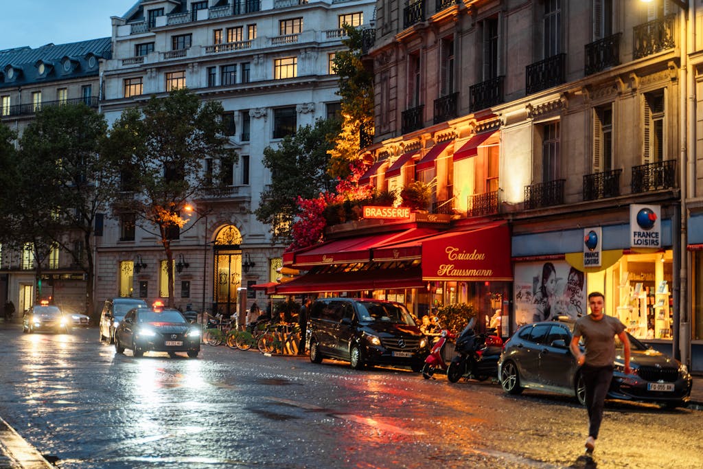 Captivating Paris nightlife with illuminated brasserie and wet streets, showcasing the city's charm.