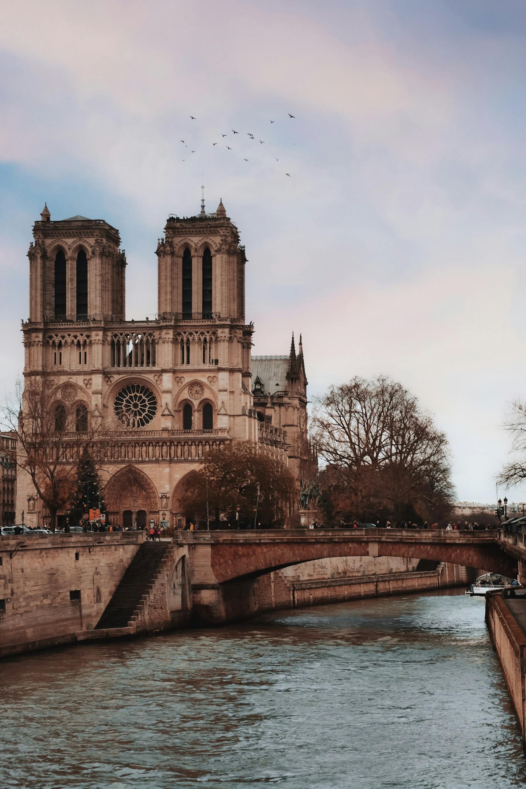 Iconic Notre Dame Cathedral beside the Seine River in Paris, France at sunset.