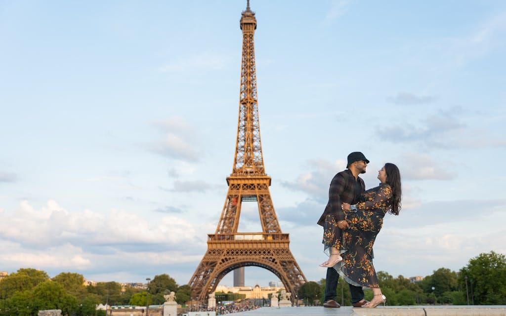 Romantic couple enjoying a moment near the Eiffel Tower with a scenic backdrop.