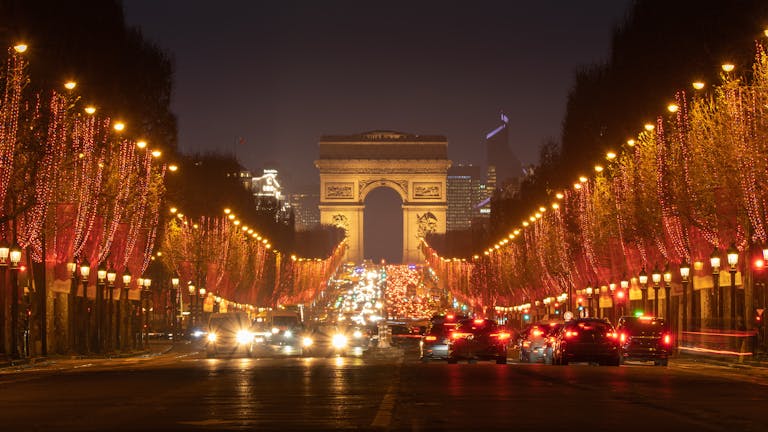 Stunning night view of the illuminated Champs-Élysées in Paris with Arc de Triomphe and festive lights.