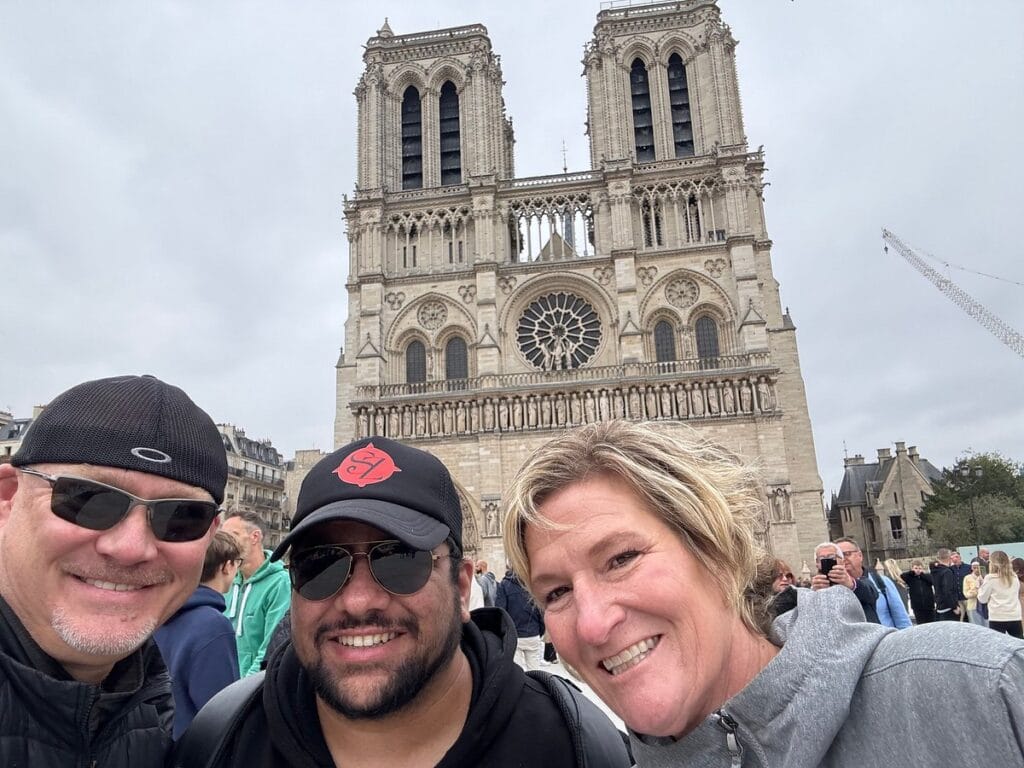 A beautifully lit street in Paris, France during the holiday season with festive lights and bustling traffic. Happy guests on Scenic Zest walking tour of Notre Dame Paris Cathedral - gallery
